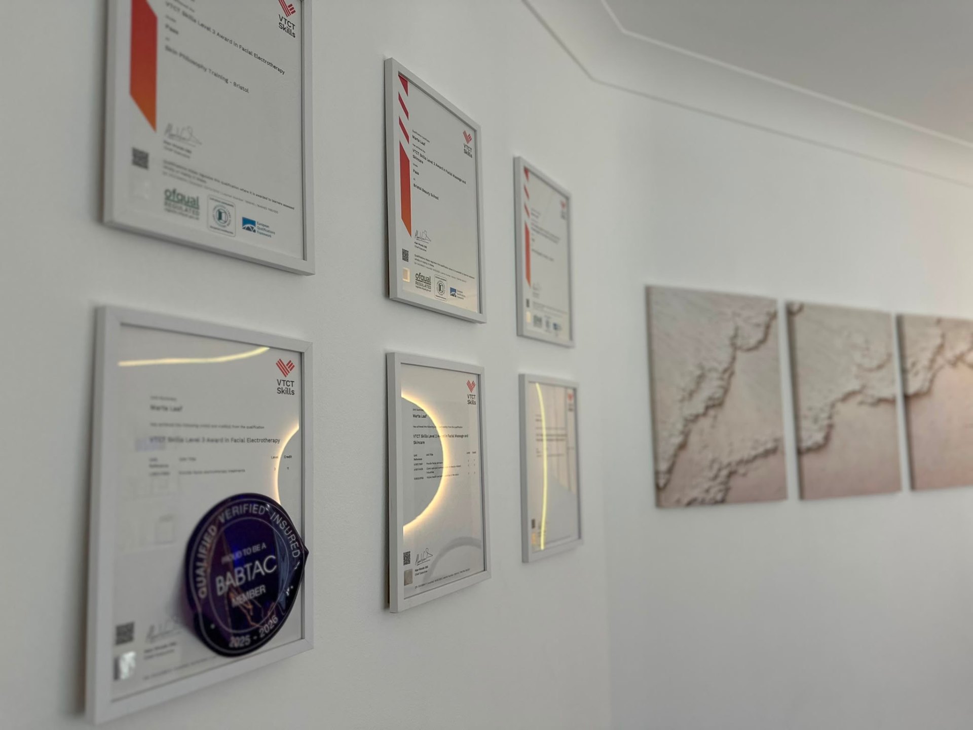 Professional skincare qualifications and certificates displayed on the studio wall