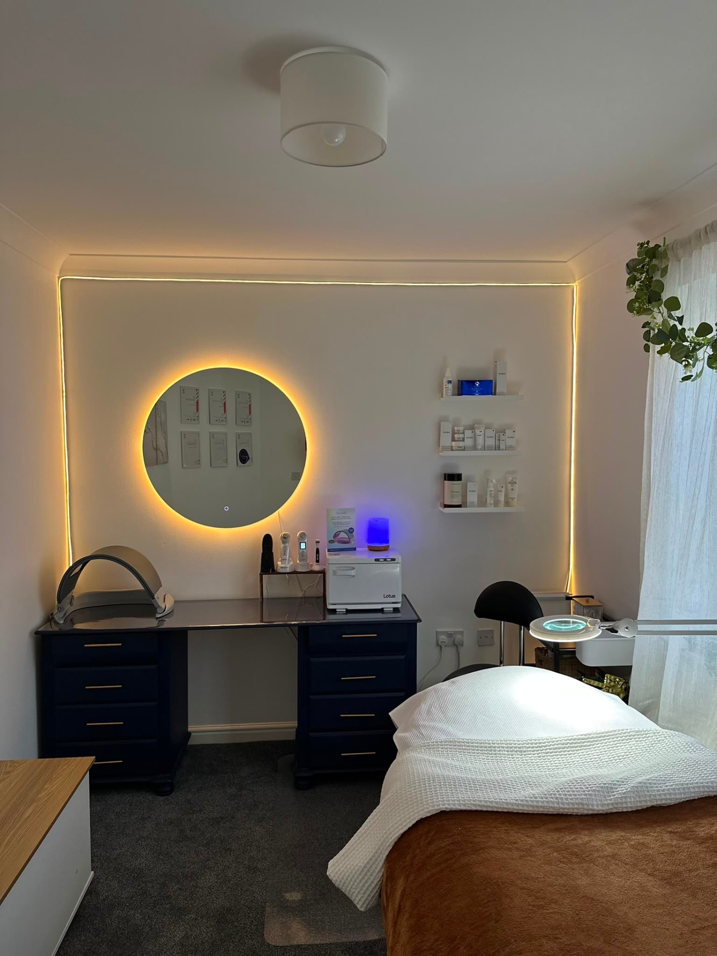 The private MH Skin Club treatment room with a covered treatment bed, glowing circular mirror, and professional skincare equipment